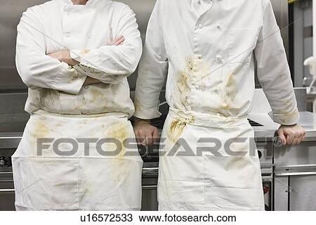 Stock Image - Dirty chefs leaning against stove. Fotosearch