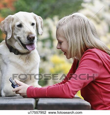 Stock Image - Dog watching girl use cell phone. Fotosearch