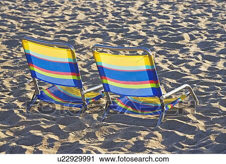 Stock Image - Empty beach chairs on sand. Fotosearch