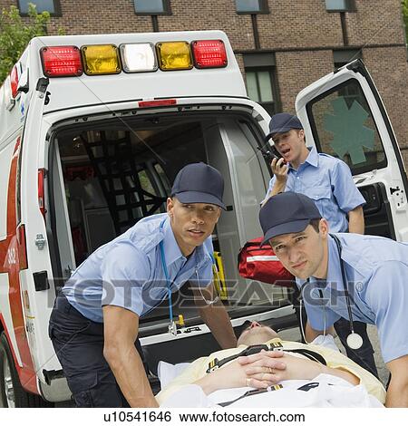 Stock Photograph - EMTs loading patient into ambulance. Fotosearch