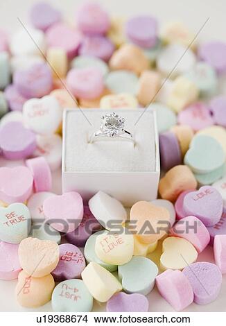 Picture - Engagement ring in box on candy hearts. Fotosearch