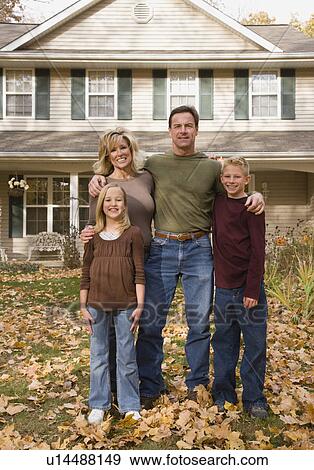 Stock Photo - Family hugging in front of house. Fotosearch