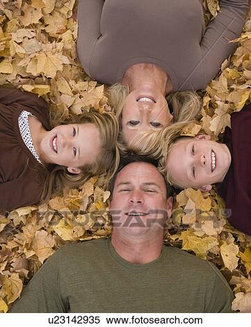 Stock Photography - Family laying in autumn leaves. Fotosearch