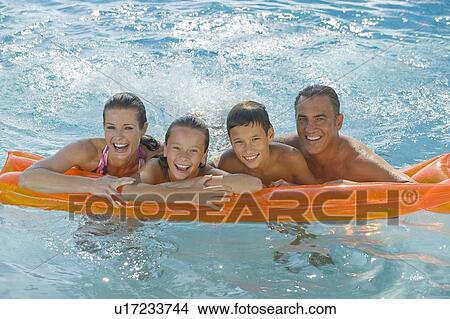 Family resting on raft in swimming pool View Large Photo Image Picture - Family resting on raft in swimming pool. Fotosearch