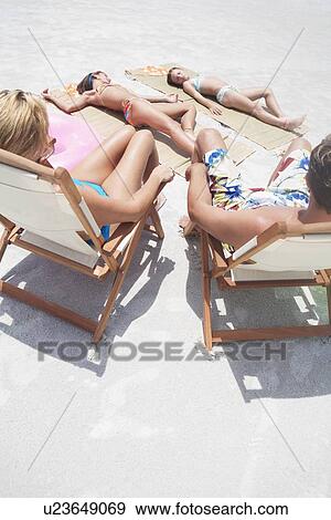 Stock Photo - Family sunbathing on beach. Fotosearch
