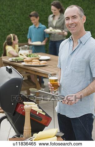Stock Photography - Family with two children barbecuing. Fotosearch