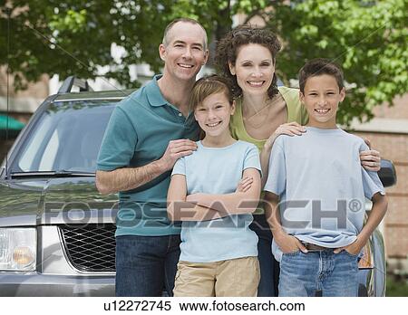 Stock Photography - Family with two children in front of car. Fotosearch