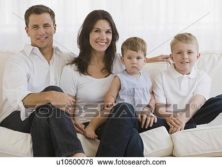 Stock Photograph - Family with two children sitting on sofa. Fotosearch