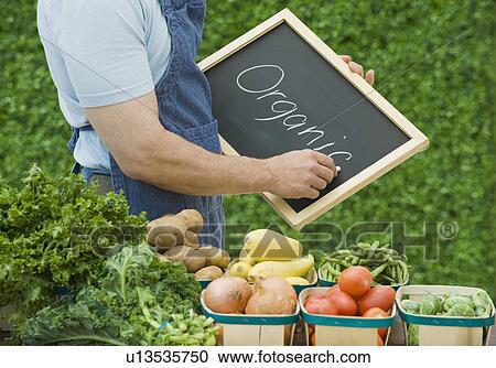 Stock Image - Farmer next to organic vegetables. Fotosearch