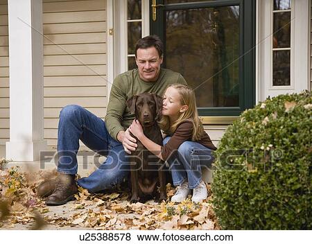 Stock Photo - Father and daughter petting dog outdoors. Fotosearch