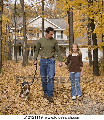 Stock Photo - Father and daughter walking dog in woods. Fotosearch