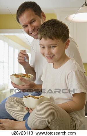 Father and son eating breakfast on kitchen counter View Large Photo Image Stock Image - Father and son eating breakfast on kitchen counter. Fotosearch