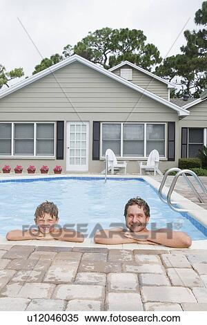 Stock Photography - Father and son leaning on edge of swimming pool. Fotosearch