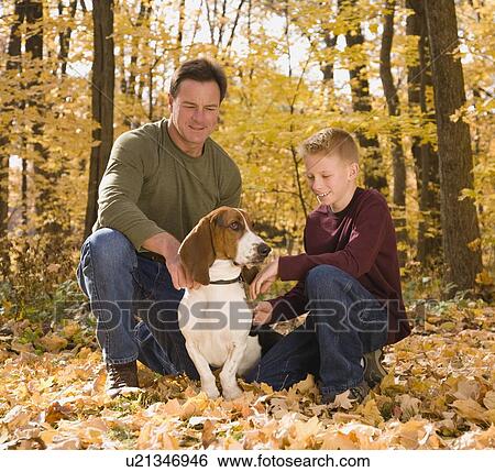Stock Photograph - Father and son petting dog outdoors. Fotosearch