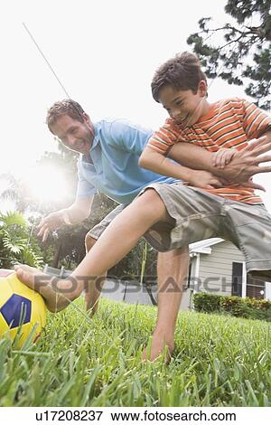 Stock Photo - Father and son playing soccer in backyard. Fotosearch