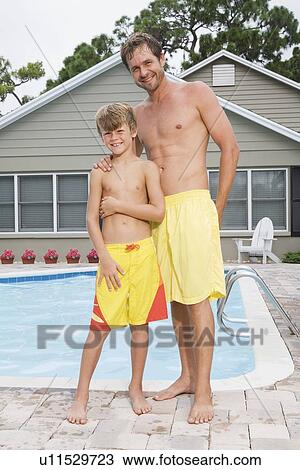 Stock Image - Father and son posing by swimming pool. Fotosearch