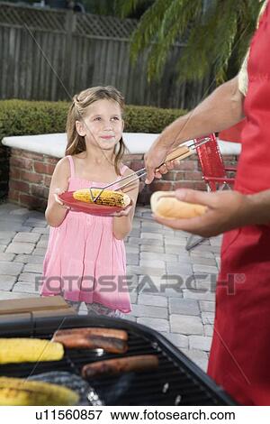 Father at barbecue grill serving daughter hot dog View Large Photo Image Stock Photo - Father at barbecue grill serving daughter hot dog. Fotosearch
