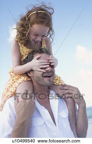 Stock Image - Father carrying daughter on shoulders. Fotosearch