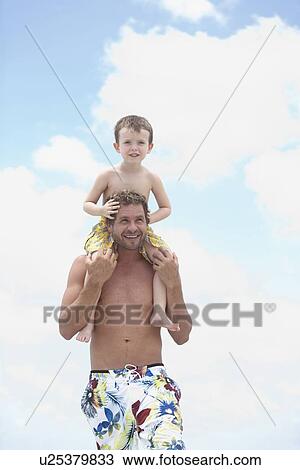 Stock Image - Father carrying son on shoulders. Fotosearch