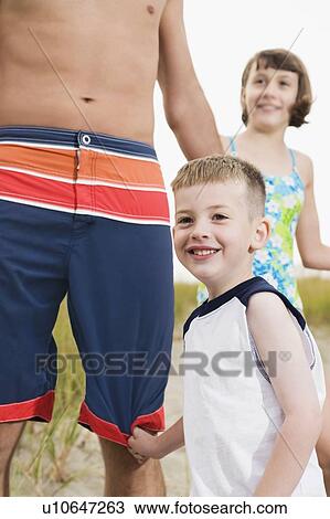 Stock Image - Father, daughter, and son on beach. Fotosearch