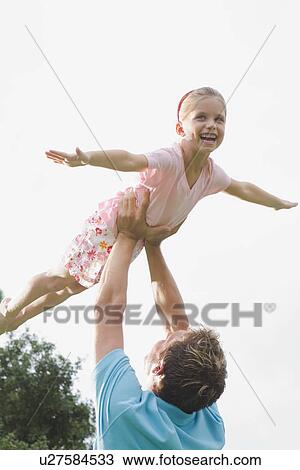 Father lifting daughter in backyard View Large Photo Image Stock Image - Father lifting daughter in backyard. Fotosearch