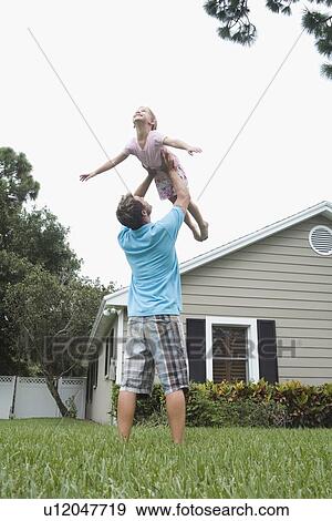 Father lifting daughter in backyard View Large Photo Image Stock Photo - Father lifting daughter in backyard. Fotosearch