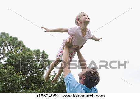Father lifting daughter in backyard View Large Photo Image Stock Photo - Father lifting daughter in backyard. Fotosearch