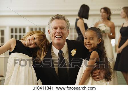Stock Image - Father of bride hugging flower girls. Fotosearch