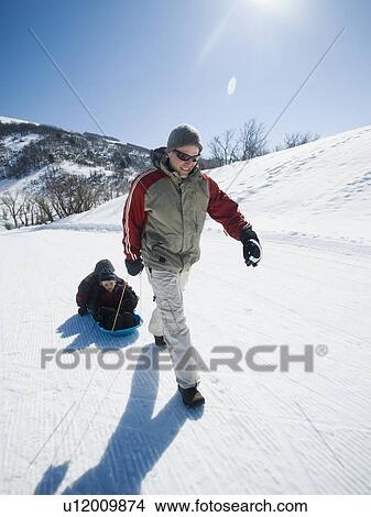 Picture - Father pulling children on sled. Fotosearch