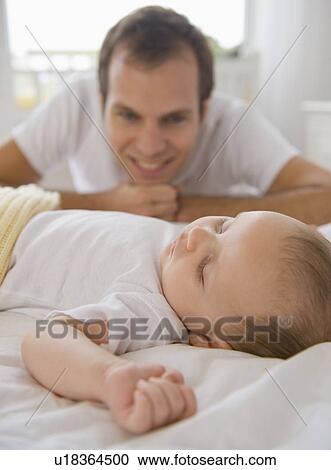 Stock Image - Father watching baby son sleep. Fotosearch