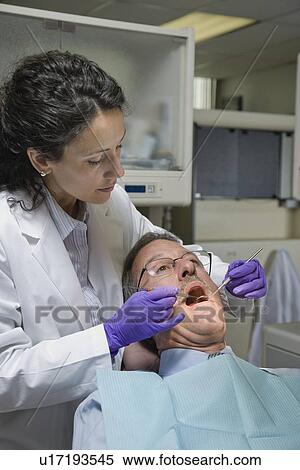 Stock Photography - Female dentist examining patient. Fotosearch
