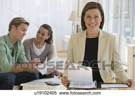 Stock Photography - Female financial advisor with couple in background. Fotosearch