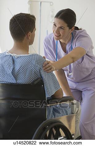 Stock Image - Female nurse with hand on patient’s shoulder. Fotosearch