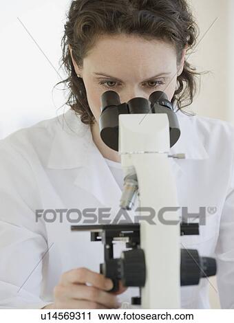 Stock Image - Female scientist looking into microscope. Fotosearch