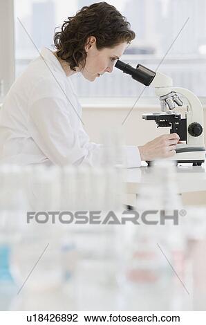 Stock Image - Female scientist looking into microscope. Fotosearch