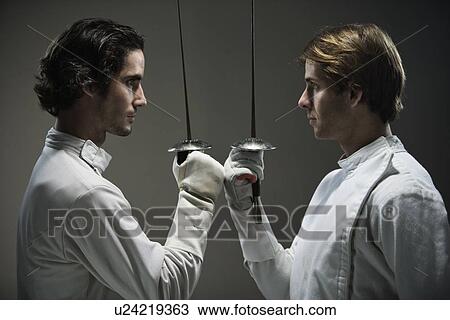 Stock Image - Fencers facing off with fencing foils. Fotosearch