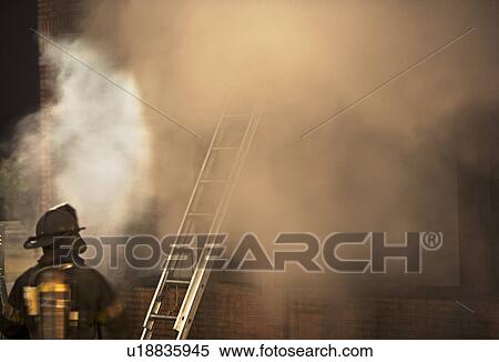 Firefighter standing outside burning building View Large Photo Image Stock Photography - Firefighter standing outside burning building. Fotosearch