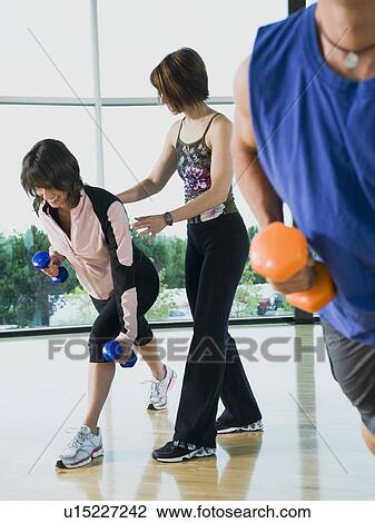 Fitness instructor helping woman lunge with dumbbells View Large Photo Image Stock Image - Fitness instructor helping woman lunge with dumbbells. Fotosearch