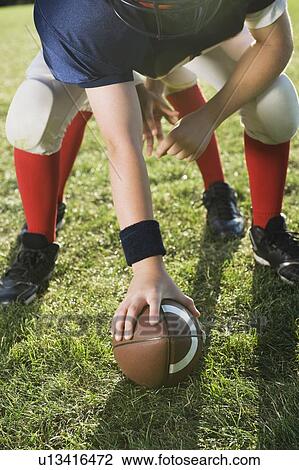Stock Image - Football center preparing to snap football. Fotosearch
