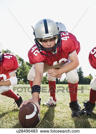 Stock Image - Football center preparing to snap football. Fotosearch
