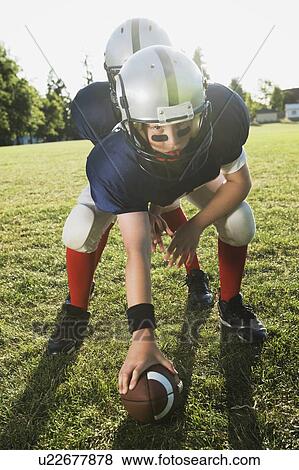 Stock Photo - Football center preparing to snap football. Fotosearch
