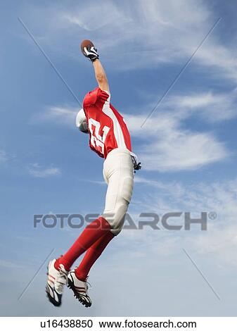 Football player in mid-air reaching for football View Large Photo Image Stock Image - Football player in mid-air reaching for football. Fotosearch