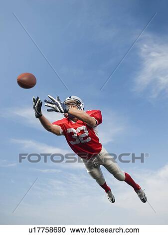 Football player in mid-air reaching for football View Large Photo Image Stock Image - Football player in mid-air reaching for football. Fotosearch