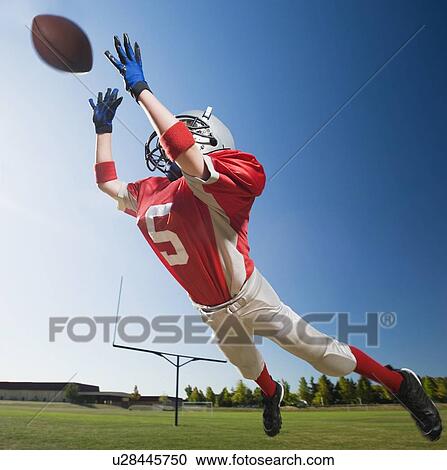 Football player in mid-air reaching for football View Large Photo Image Stock Image - Football player in mid-air reaching for football. Fotosearch