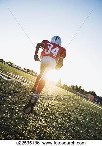 Football player running on field with football View Large Photo Image Stock Photograph - Football player running on field with football. Fotosearch