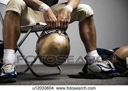 Picture - Football player sitting in locker room. Fotosearch