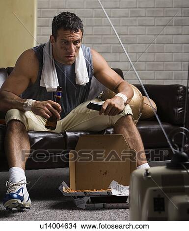 Football player watching game on sofa with beer View Large Photo Image Picture - Football player watching game on sofa with beer. Fotosearch