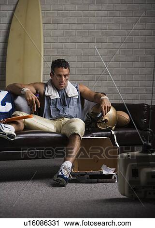 Football player watching game on sofa View Large Photo Image Stock Image - Football player watching game on sofa. Fotosearch