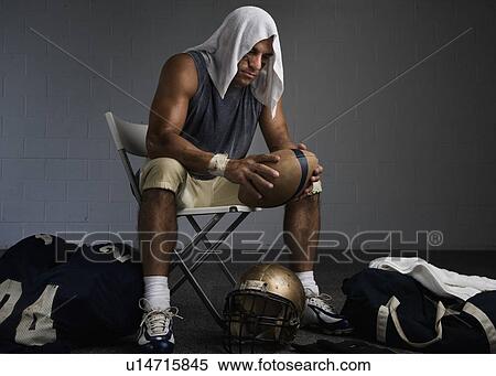 Stock Photography - Football player with towel on head in locker room. Fotosearch