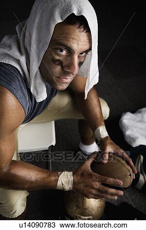 Stock Image - Football player with towel on head holding football. Fotosearch